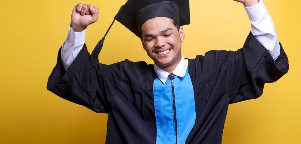 A student in convocation gown celebrating